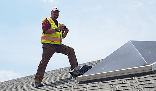 Glenn Ross standing on the roof of a home preforming an inspection.